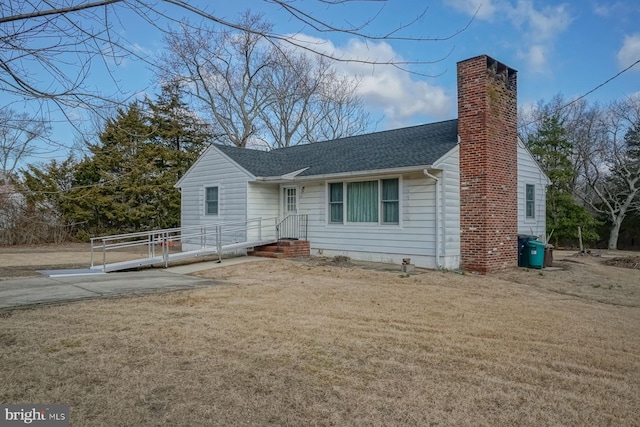 view of front of house with a front yard, a chimney, and roof with shingles