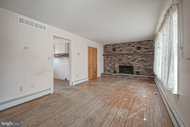 unfurnished living room featuring a baseboard radiator, visible vents, and hardwood / wood-style flooring