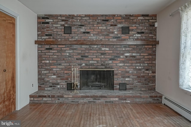 details with a baseboard heating unit, a brick fireplace, and wood finished floors