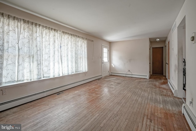 empty room featuring a baseboard heating unit and hardwood / wood-style flooring