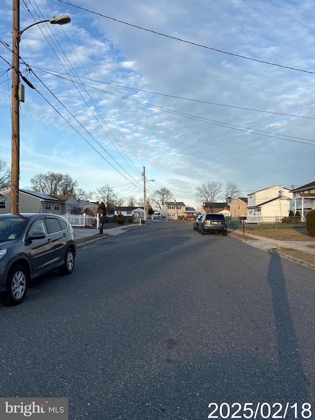 view of street with sidewalks, a residential view, street lights, and curbs