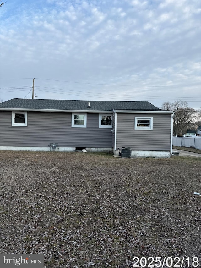 back of house featuring a shingled roof, fence, and central AC