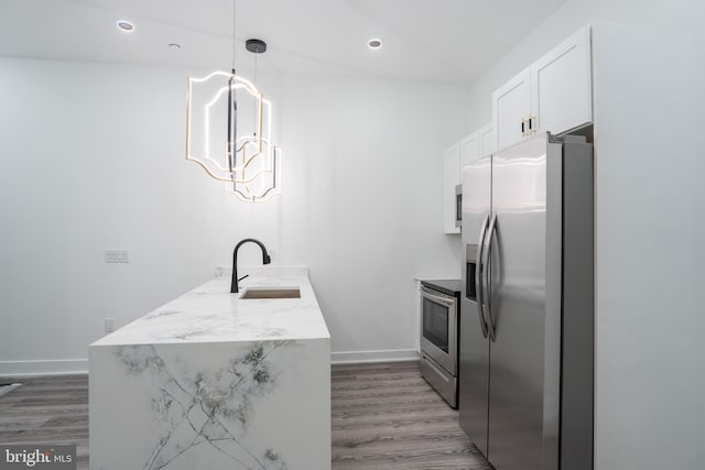 kitchen with light stone counters, pendant lighting, appliances with stainless steel finishes, white cabinetry, and a sink