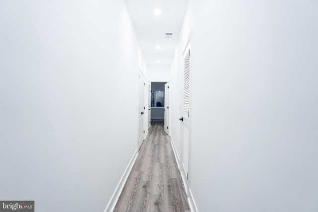 hall with light wood finished floors, baseboards, and recessed lighting