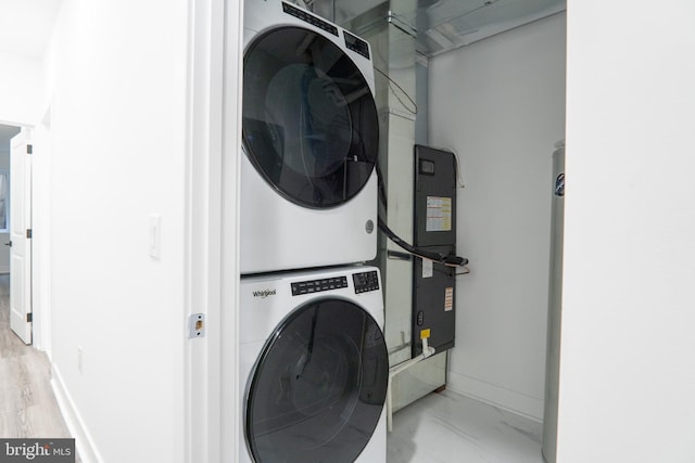 laundry area featuring laundry area, marble finish floor, stacked washer and clothes dryer, and baseboards