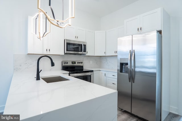 kitchen featuring stainless steel appliances, hanging light fixtures, white cabinets, a sink, and light stone countertops