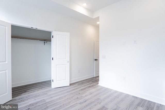 unfurnished bedroom featuring baseboards, a closet, recessed lighting, and light wood-style floors