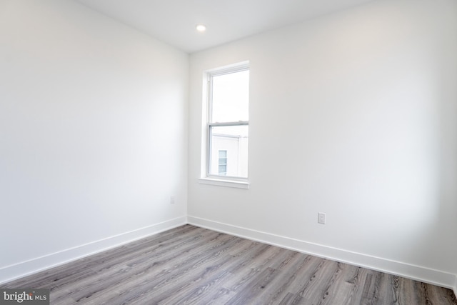 spare room featuring recessed lighting, light wood-type flooring, and baseboards