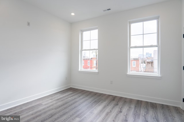 empty room featuring visible vents, light wood finished floors, and baseboards