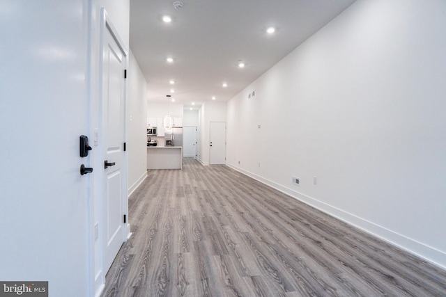 interior space with baseboards, light wood-style flooring, and recessed lighting