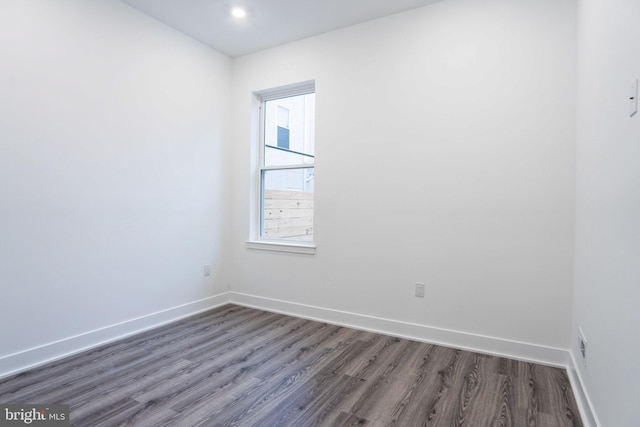 unfurnished room featuring dark wood-type flooring and baseboards