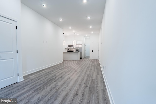 unfurnished living room with light wood finished floors, baseboards, and recessed lighting