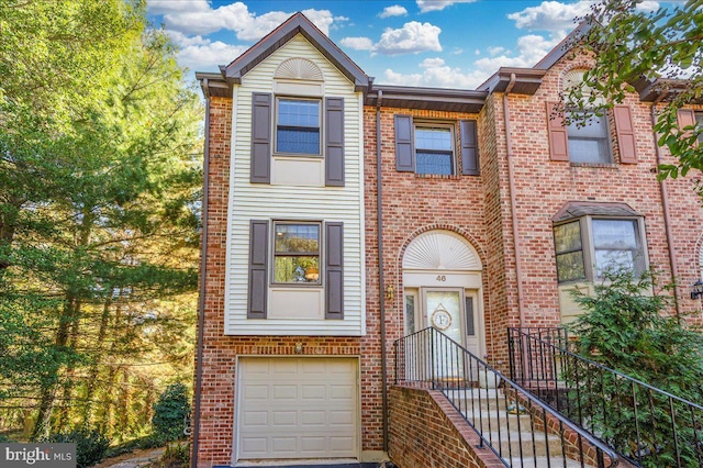 townhome / multi-family property with a garage and brick siding