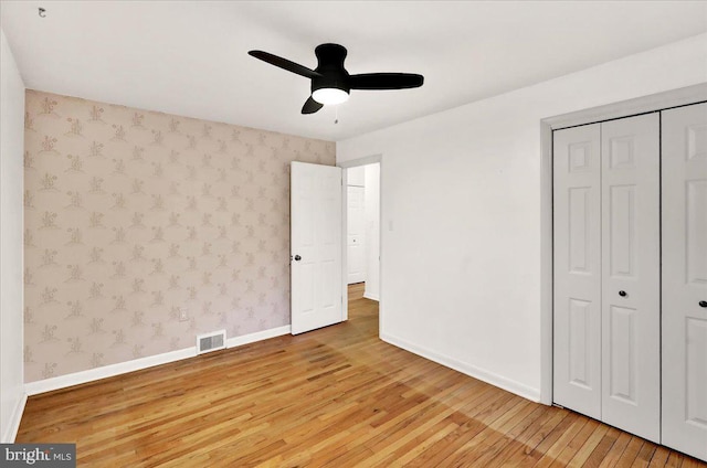 unfurnished bedroom featuring baseboards, light wood finished floors, visible vents, and wallpapered walls