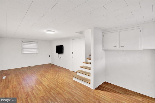 basement with light wood-style flooring and stairway