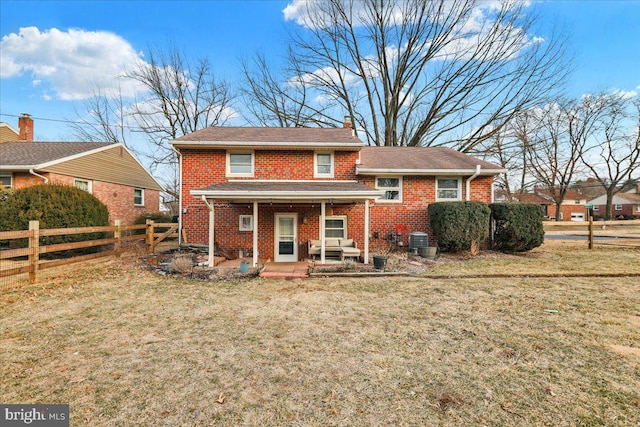 view of front of house featuring central AC, brick siding, a front lawn, and fence