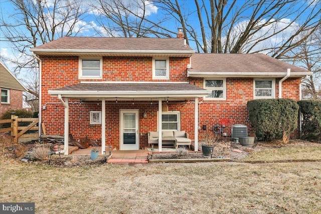 split level home featuring cooling unit, brick siding, fence, a front lawn, and a chimney