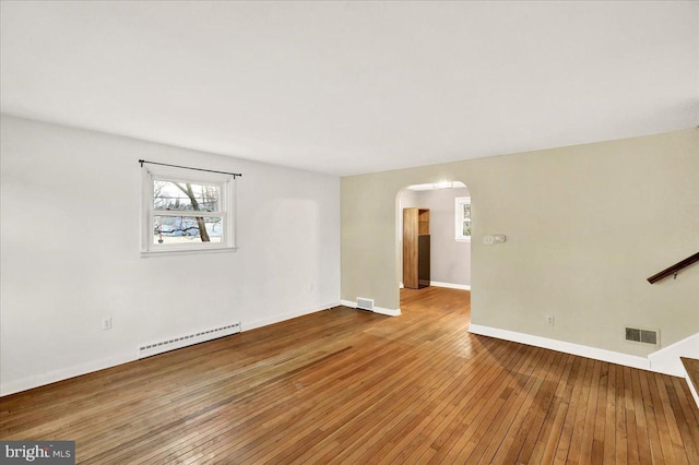 interior space featuring a baseboard radiator, visible vents, arched walkways, and hardwood / wood-style floors