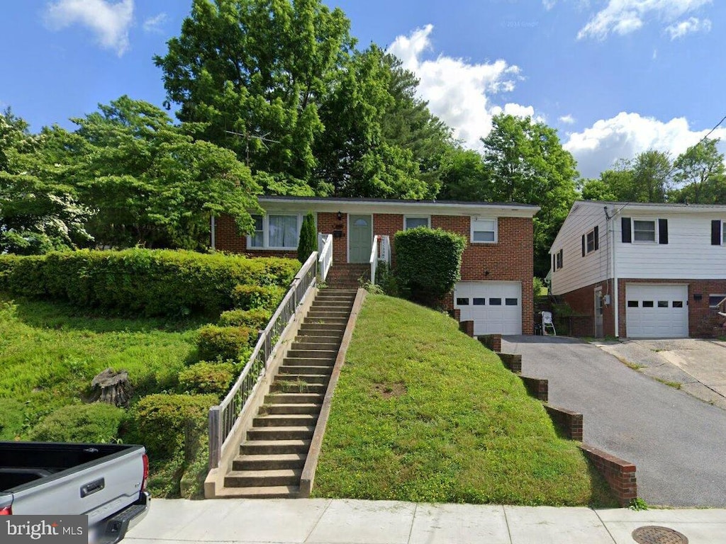 view of front facade with a garage, driveway, stairway, and brick siding