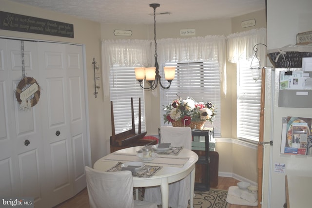 dining area with visible vents, a notable chandelier, baseboards, and wood finished floors