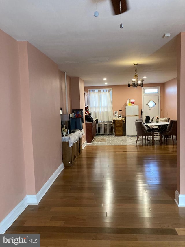 interior space featuring an inviting chandelier, baseboards, radiator heating unit, and wood finished floors