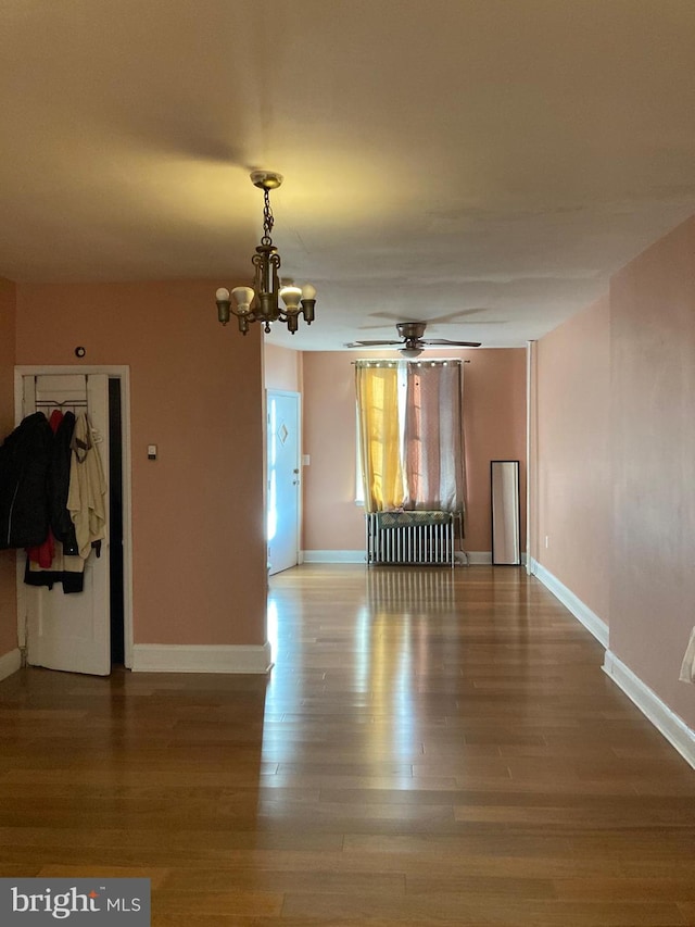 interior space featuring baseboards, wood finished floors, and ceiling fan with notable chandelier