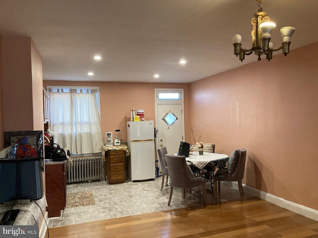 dining space with an inviting chandelier, radiator heating unit, baseboards, and light wood-style flooring