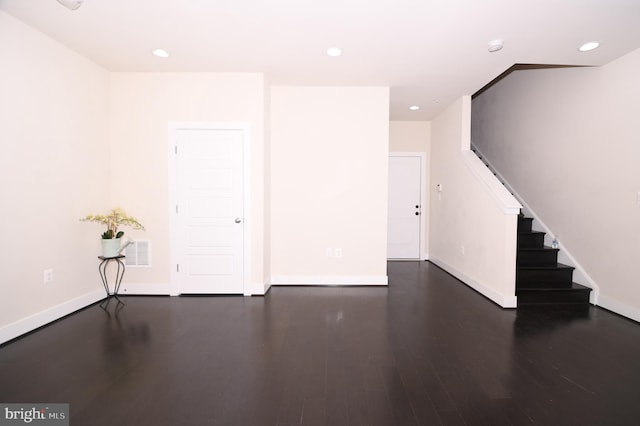 empty room featuring stairs, dark wood finished floors, and recessed lighting