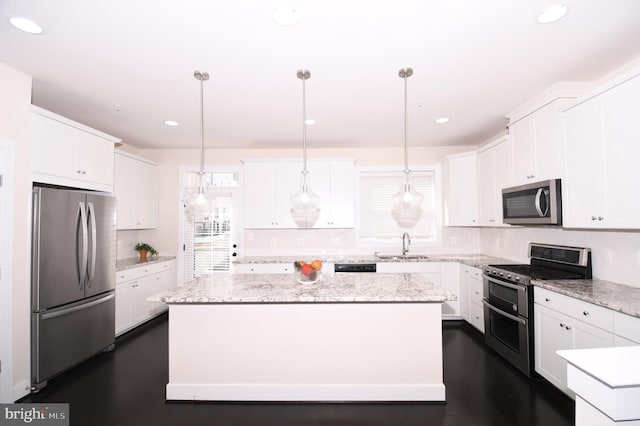 kitchen with a kitchen island, appliances with stainless steel finishes, white cabinets, and decorative light fixtures