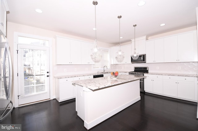 kitchen featuring appliances with stainless steel finishes, white cabinetry, and pendant lighting