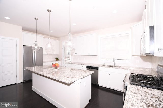 kitchen featuring light stone counters, stainless steel appliances, hanging light fixtures, white cabinetry, and a kitchen island