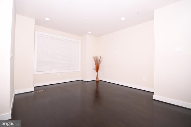 empty room with dark wood-style floors, baseboards, and recessed lighting