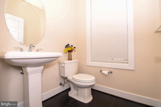 bathroom with toilet, baseboards, and wood finished floors