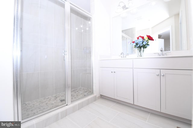 full bathroom with double vanity, a stall shower, a sink, and tile patterned floors