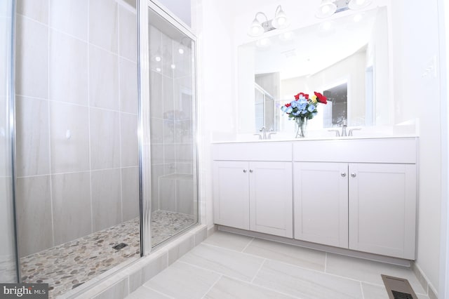 bathroom featuring a stall shower, visible vents, a sink, and double vanity