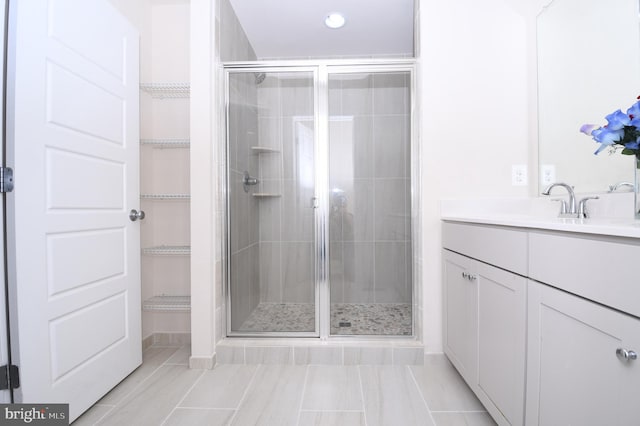 bathroom with a stall shower, vanity, and a spacious closet