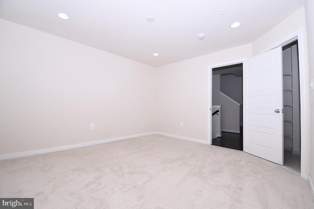 unfurnished room with baseboards, recessed lighting, and light colored carpet