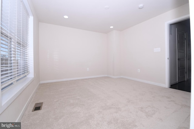 spare room with carpet floors, recessed lighting, visible vents, and baseboards