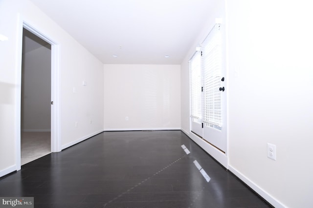 unfurnished room featuring dark wood-style floors and baseboards