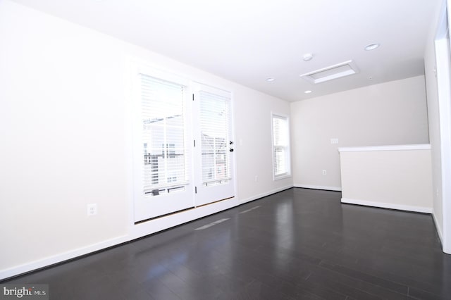 spare room featuring recessed lighting, dark wood finished floors, attic access, and baseboards