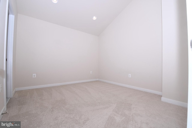 spare room with lofted ceiling, recessed lighting, baseboards, and light colored carpet