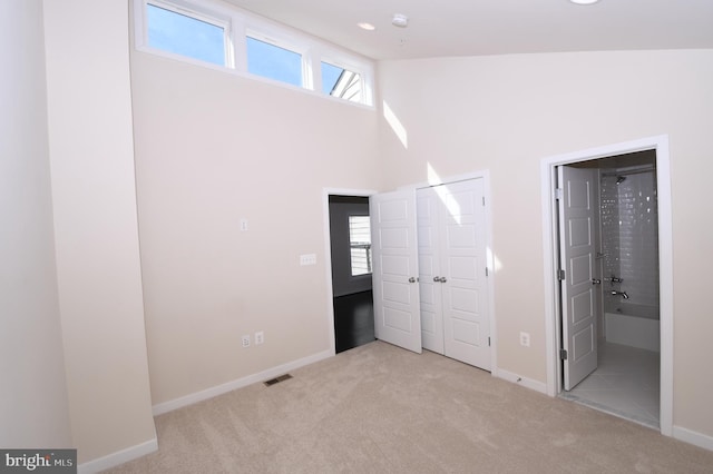 unfurnished bedroom featuring light colored carpet, visible vents, baseboards, and multiple windows