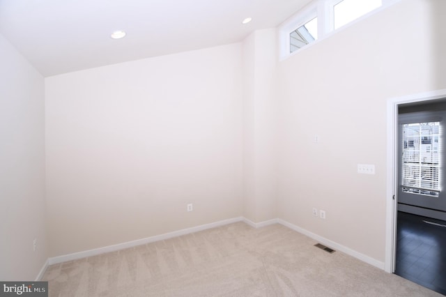 unfurnished room with baseboards, visible vents, and light colored carpet