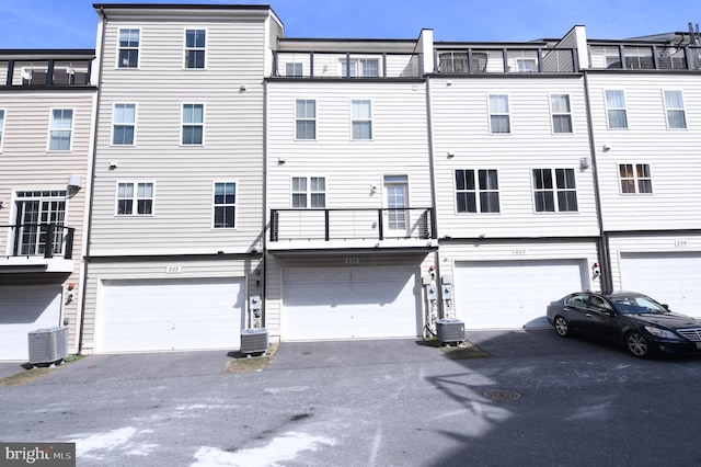 back of house featuring a garage, driveway, and central AC unit