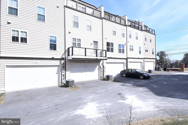 rear view of house featuring a garage, driveway, and central air condition unit