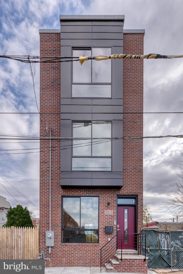 view of front of home featuring brick siding and fence