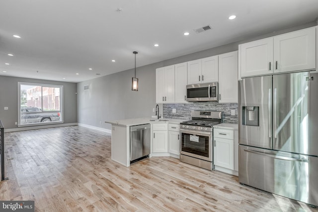 kitchen featuring stainless steel appliances, a peninsula, visible vents, open floor plan, and hanging light fixtures