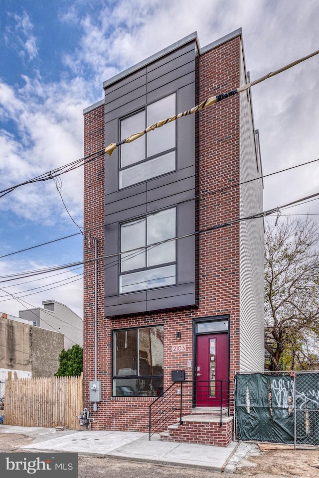 view of front facade featuring brick siding and fence