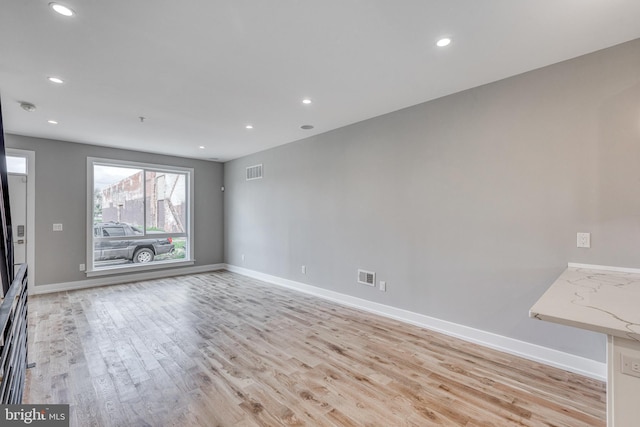 unfurnished living room with baseboards, visible vents, and light wood finished floors