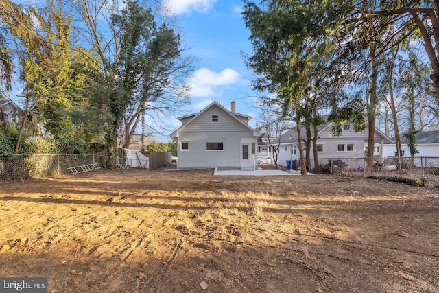 rear view of house featuring a chimney, a patio area, and a fenced backyard